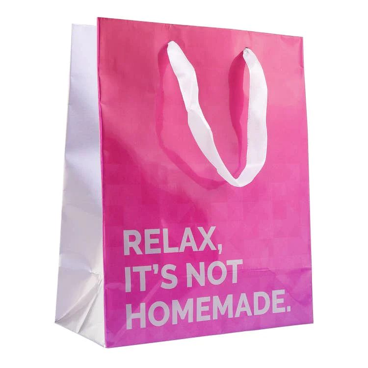 hot pink gift bag with white handle that reads,"relax, it's not homemade."