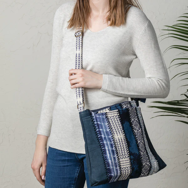 blue patchwork shoulder bag worn by woman with white sweater and blue denim pants