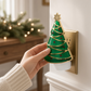 Mellow Monkey Christmas tree fragrance warmer with green enamel, gold trim, and red ornaments plugged into a wall.