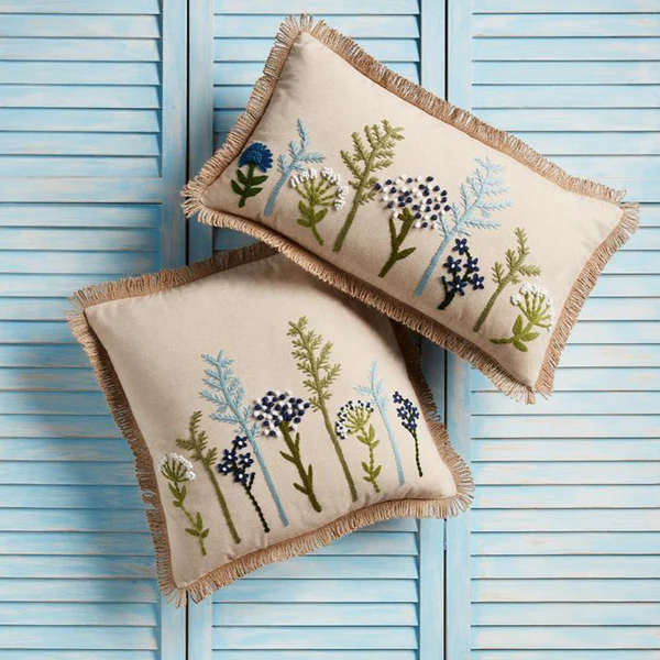 two Floral Embroidered Pillows against baby blue shutters