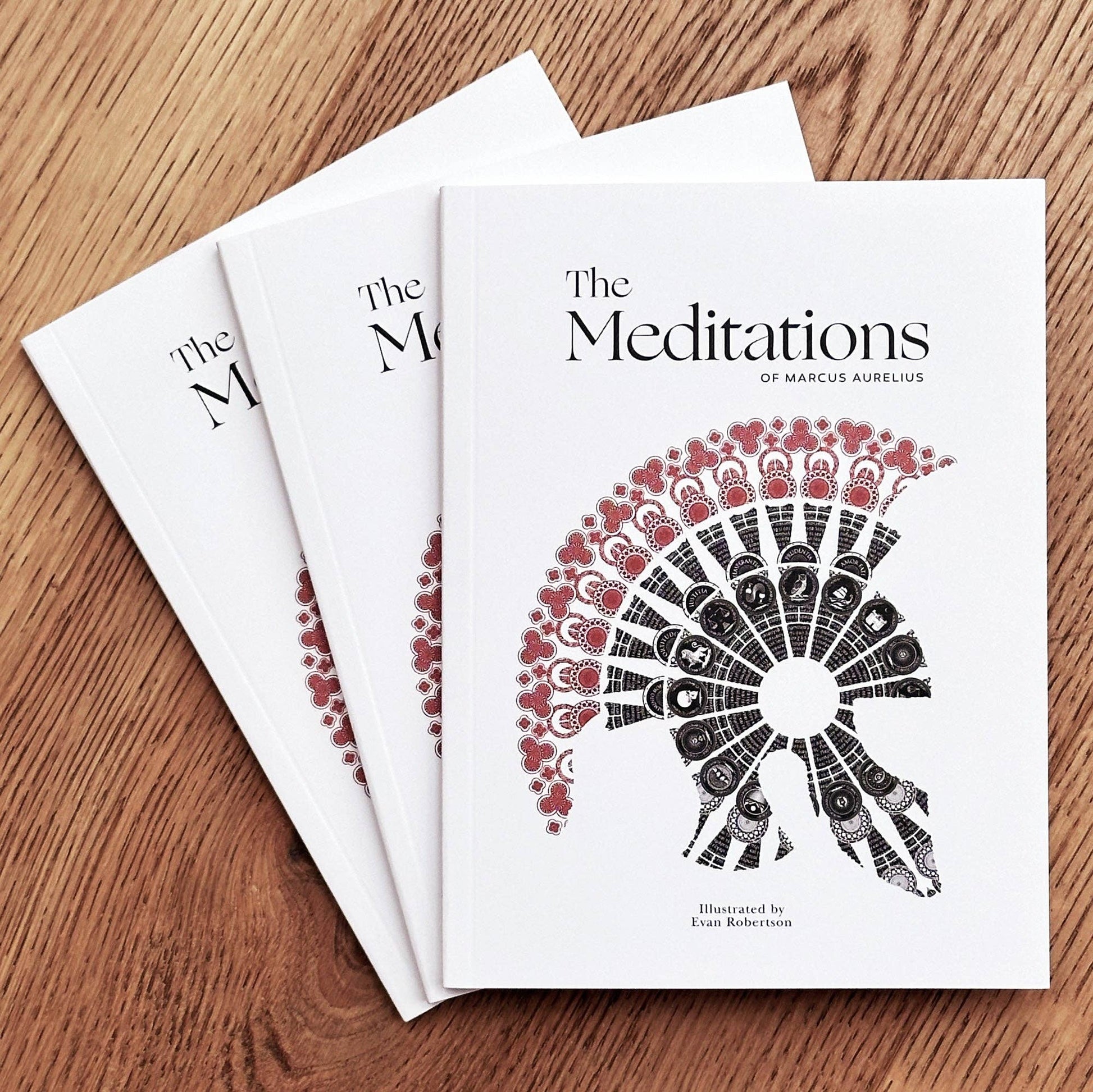 Three copies of 'The Meditations' by Marcus Aurelius on a wooden surface