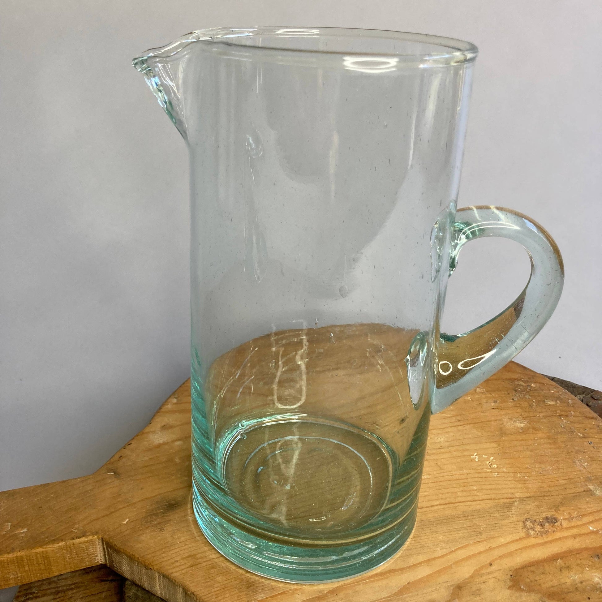 Clear glass pitcher on a wooden surface with a plain background