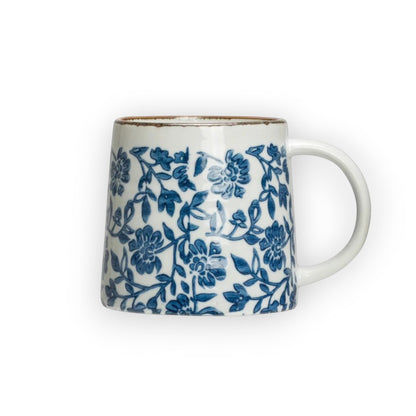 Mellow Monkey hand-stamped stoneware mug with blue floral design and gold rim detail. Microwave, dishwasher, and oven safe.