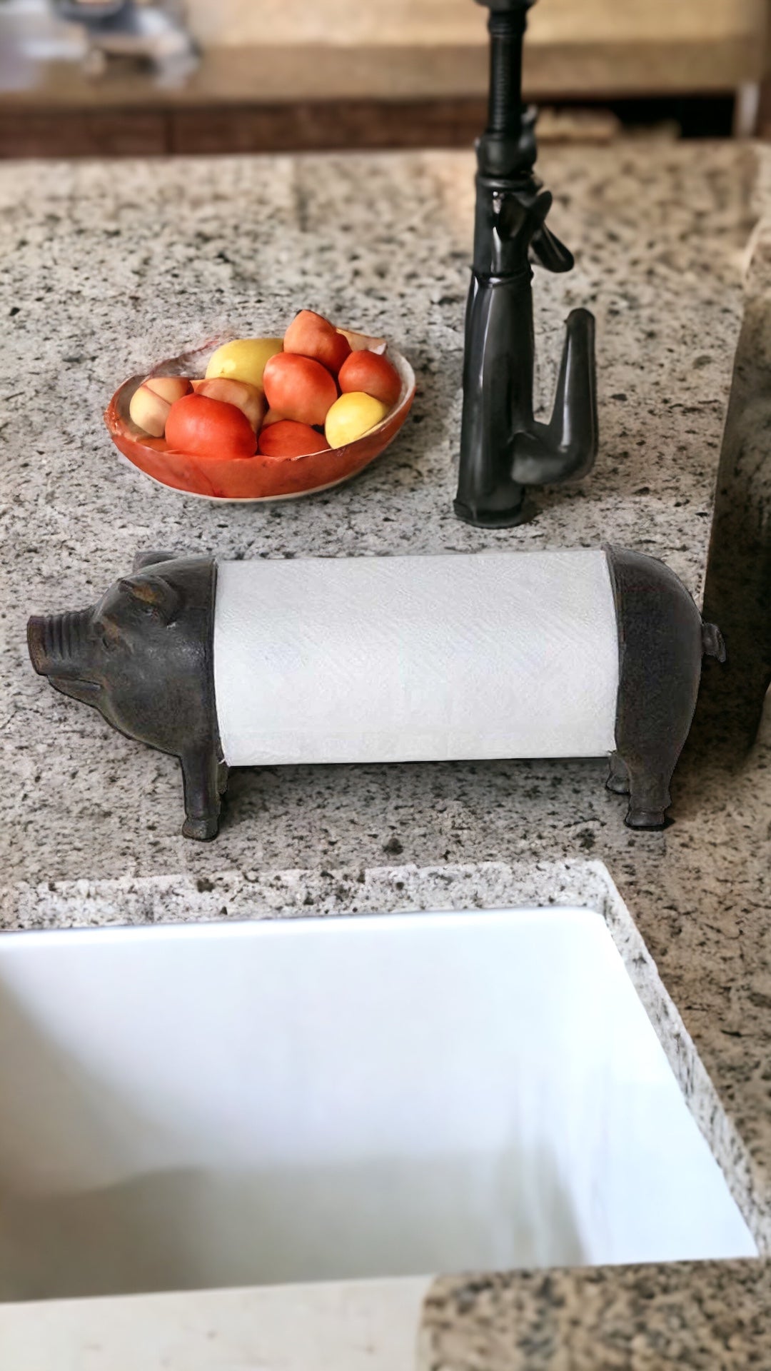 pig shaped paper towel holder on a granite countertop near a white basin sink