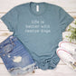 Blue t-shirt with 'Life is better with rescue dogs' text, denim shorts, and white sneakers on a wooden surface.