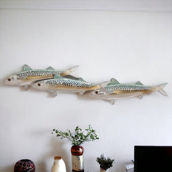 three metal fish on white wall