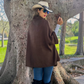 Mellow Monkey dark brown knit cape cardigan with button neck detail worn over jeans and a cowboy hat