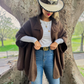Mellow Monkey dark brown knit cape cardigan with button neck detail worn over a white top and blue jeans.