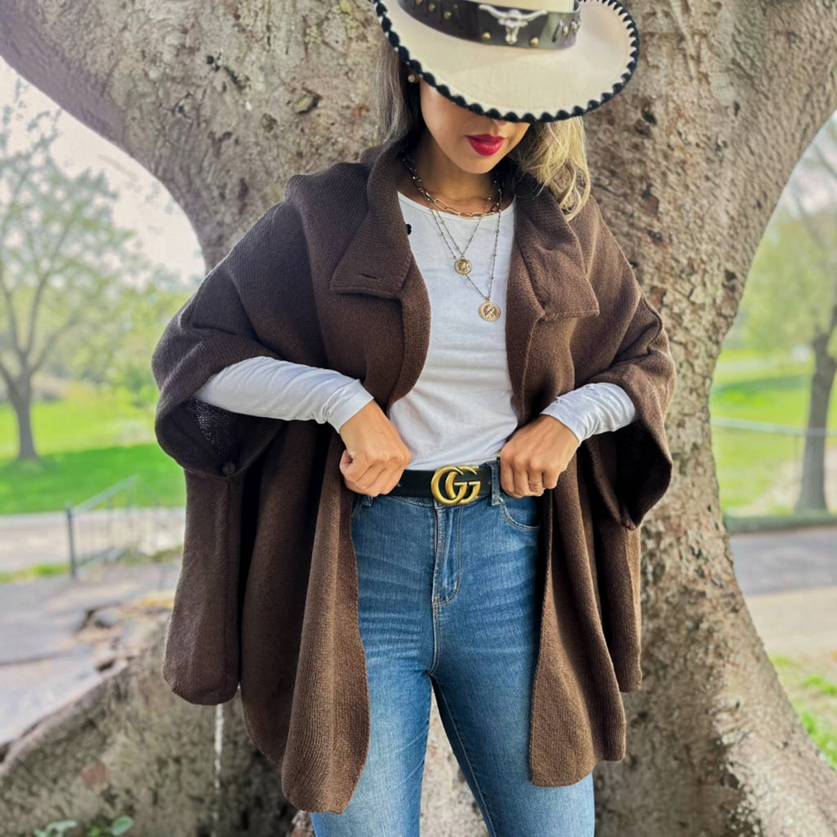 Mellow Monkey dark brown knit cape cardigan with button neck detail worn over a white top and blue jeans.