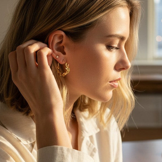 Mellow Monkey 18k gold plated hoop earrings with a twisted design, worn by a woman indoors.
