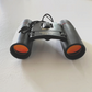Mellow Monkey 30x60 compact folding binoculars with orange-tinted lenses for hunting, camping, and bird watching.