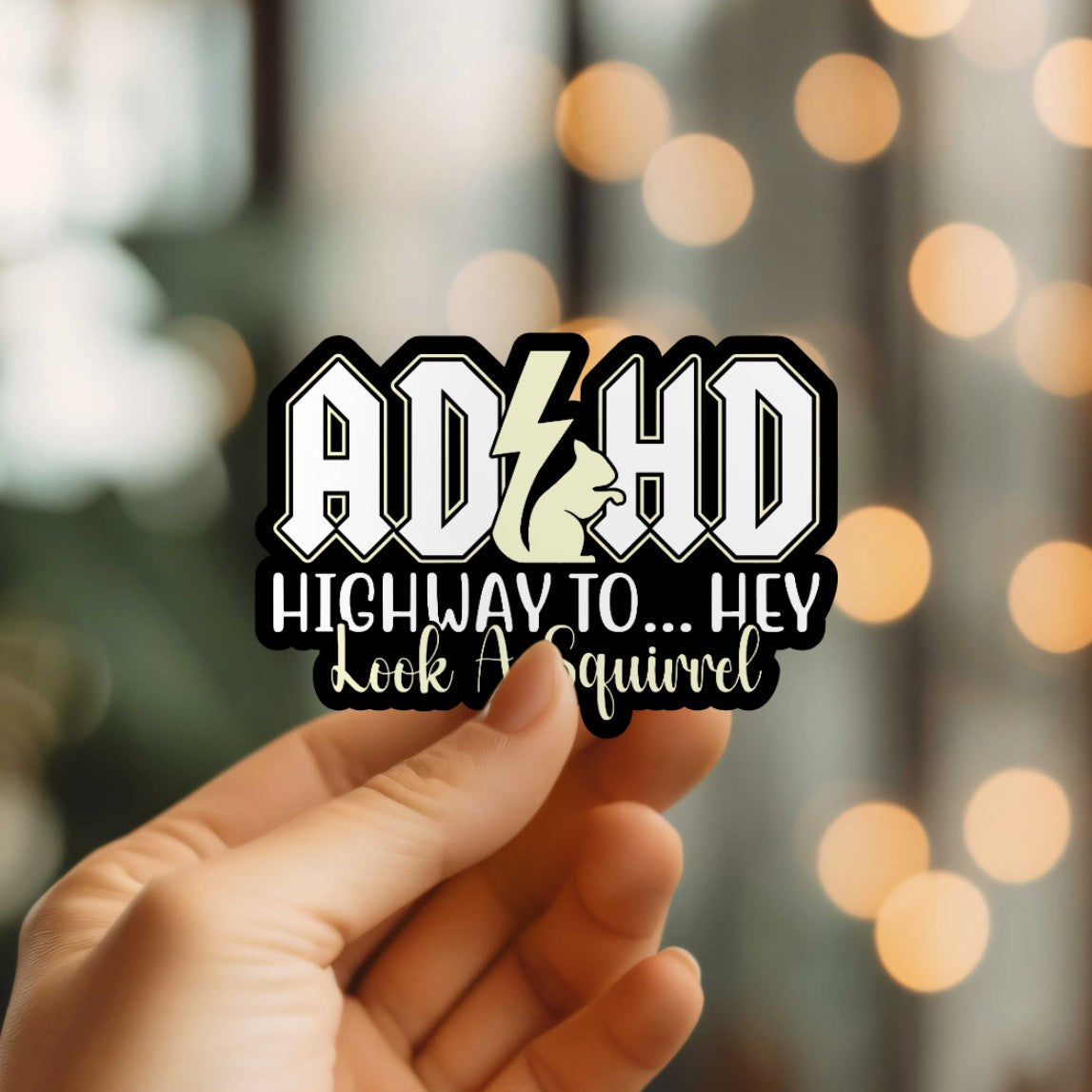 Mellow Monkey ADHD Hey Look A Squirrel waterproof vinyl sticker held in hand against a blurred bokeh background.