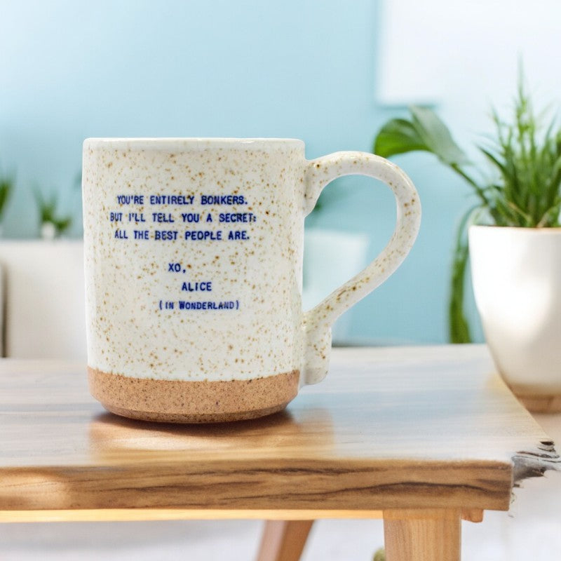 Mellow Monkey handmade ceramic mug with speckled finish and Alice in Wonderland quote on a wooden table