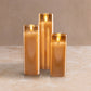 Mellow Monkey set of three amber glass flameless LED pillar candles with a warm flickering glow on a stone surface.