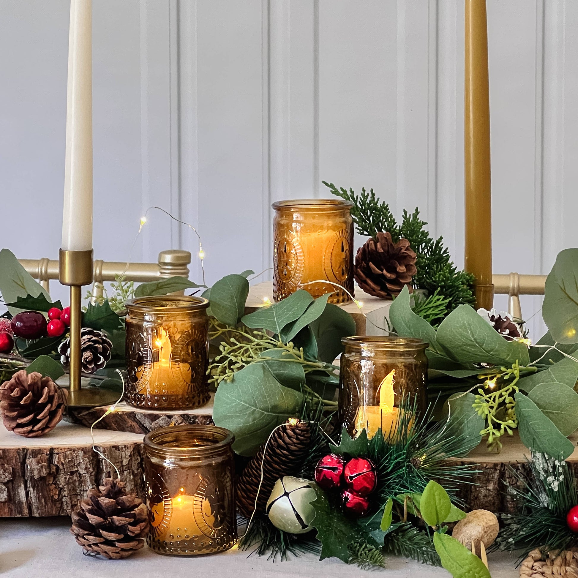 Mellow Monkey set of 4 vintage amber glass tea light holders styled with eucalyptus, pinecones, and holiday decor.