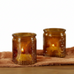 Mellow Monkey set of two vintage amber glass tea light holders with embossed fleur-de-lis detail on a rustic cloth