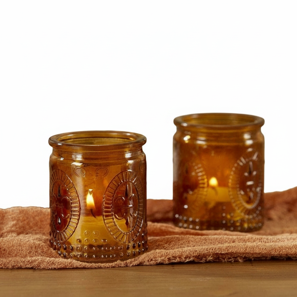 Mellow Monkey set of two vintage amber glass tea light holders with embossed fleur-de-lis detail on a rustic cloth