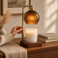 Mellow Monkey Amber Sphere Candle Warmer Lamp with a brushed gold stem and amber glass dome on a wooden base.