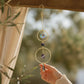 Mellow Monkey amethyst suncatcher ornament with bronze rings and crystals hanging in a sunny window