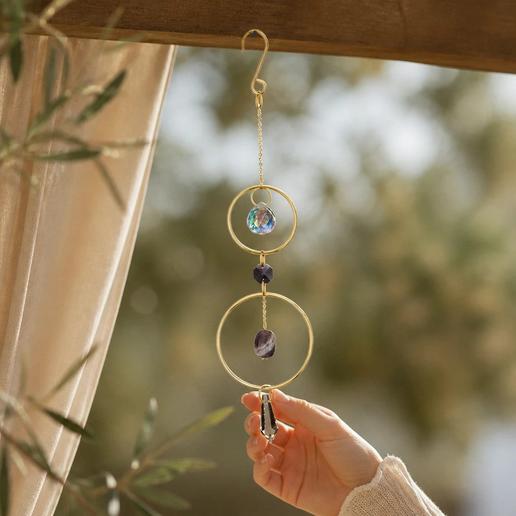 Mellow Monkey amethyst suncatcher ornament with bronze rings and crystals hanging in a sunny window
