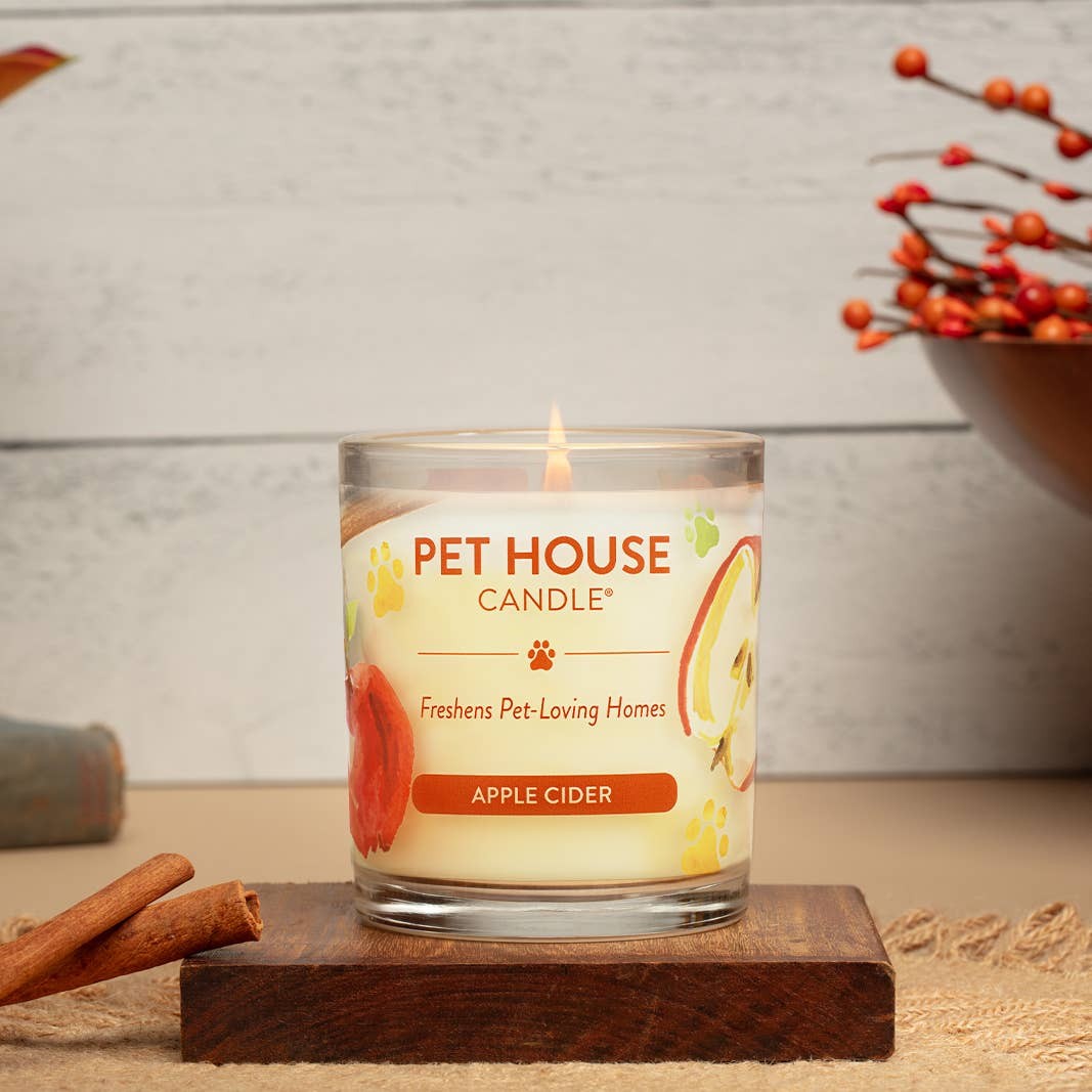 Mellow Monkey Pet House Apple Cider scented candle in a glass jar with cinnamon sticks on a wooden base