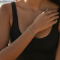 Mellow Monkey aqua and white stretch seed bead bracelet worn by a woman on a sunny beach in a black swimsuit.