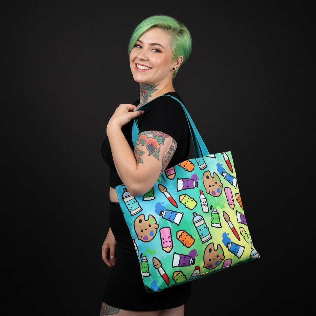 Mellow Monkey art supplies tote bag with paint tubes, palettes, and brushes on a rainbow gradient background. Features dual straps and a zippered closure.