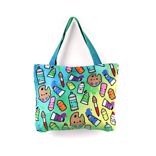 Mellow Monkey art supplies tote bag with paint tubes, palettes, brushes, and spray cans on a rainbow gradient background. Features dual straps and a zippered closure.