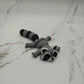 Mellow Monkey articulated grey and black 3D printed raccoon fidget toy lying flat on a white marble surface