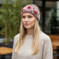 Mellow Monkey Aubrey headband in begonia pink wool with floral embroidery worn by a blonde woman in a beige sweater