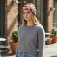 Mellow Monkey Aubrey headband in light natural wool with red floral embroidery worn by a woman outdoors