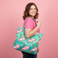 Mellow Monkey pink axolotl print tote bag with teal background and interior zippered pocket, held by a woman.