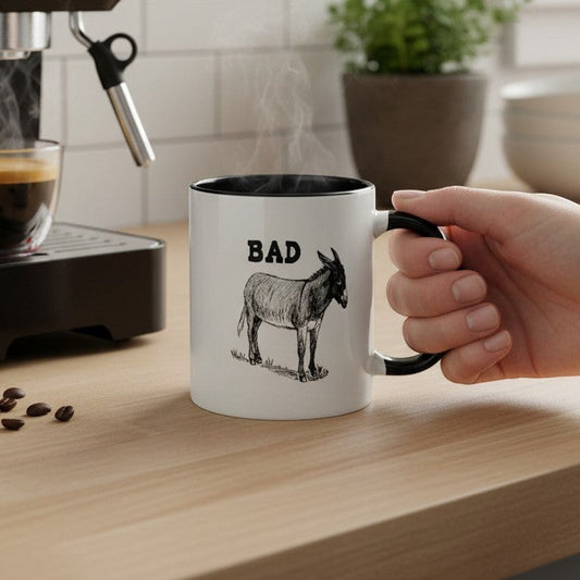 Mellow Monkey white ceramic mug with black handle and rim, featuring a black and white illustration of a donkey and the word BAD.