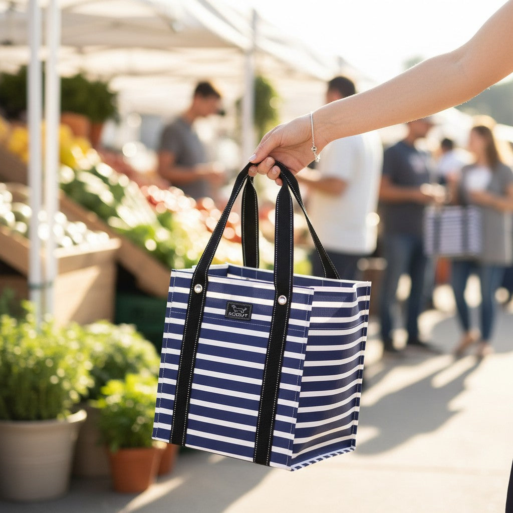 Mellow Monkey Bagette market tote in Nantucket Navy blue and white stripes held at a sunny outdoor farmers market