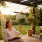 Mellow Monkey 21-inch bamboo and metal wind chime hanging outdoors, with a woman relaxing in a hammock.