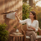Mellow Monkey bamboo wind chime with silver metal tubes, featuring a decorative bamboo top, hanging on a wooden wall.