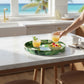 Mellow Monkey banana leaf print round resin serving tray with gold trim, 13.75 inches.