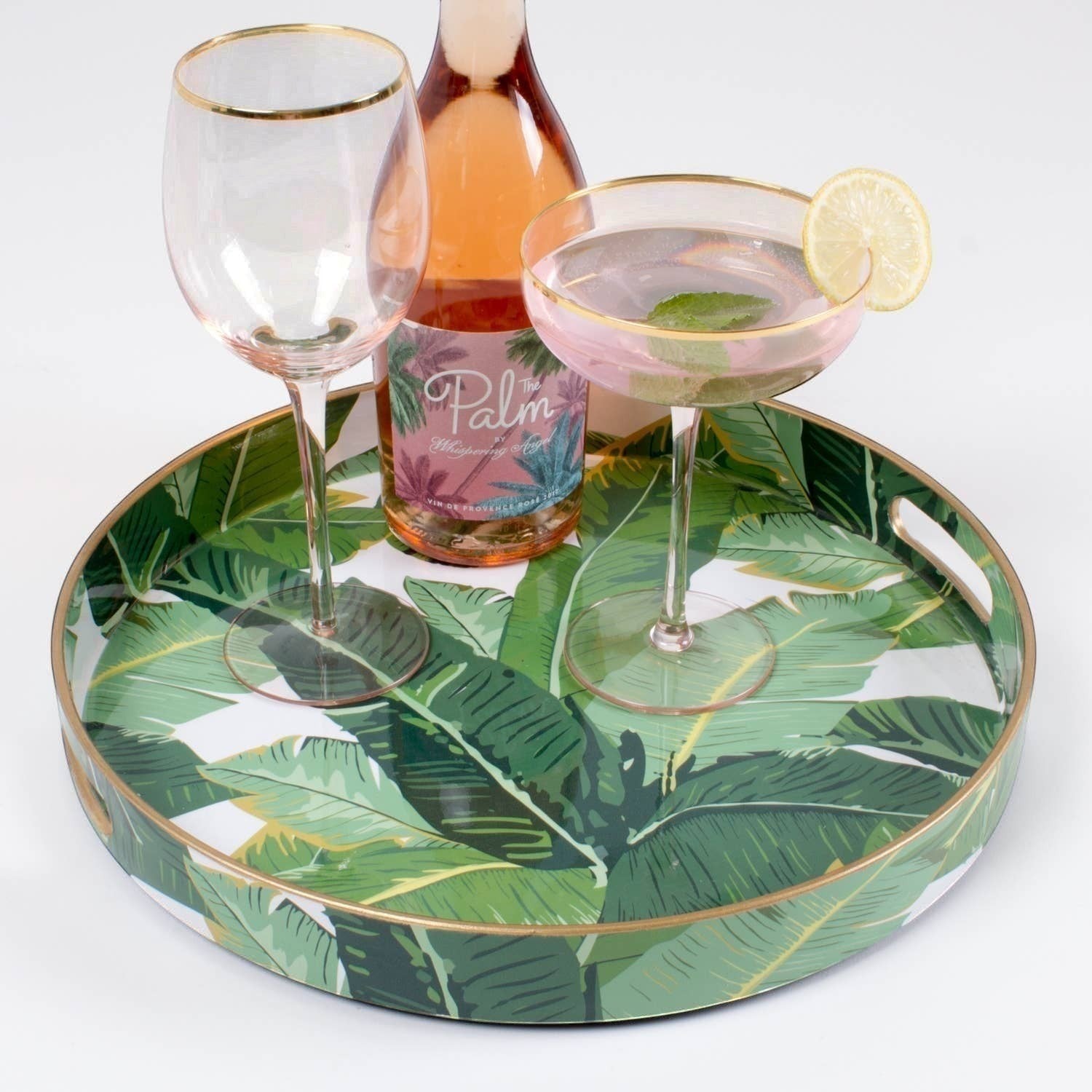 Mellow Monkey banana leaf round resin serving tray with gold trim, featuring a tropical green leaf print on white.