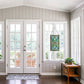 Mellow Monkey Baroque ribbon stained glass window panel with jewel tones and metal trim hanging in a bright entryway.
