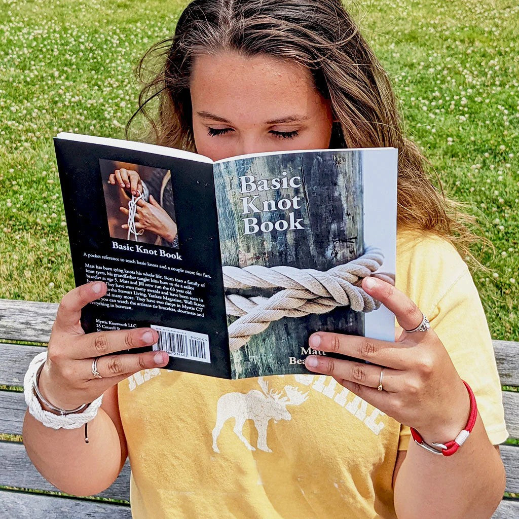 Mellow Monkey Basic Knot Book held by a woman outdoors, featuring illustrated instructions for 17 classic knots.