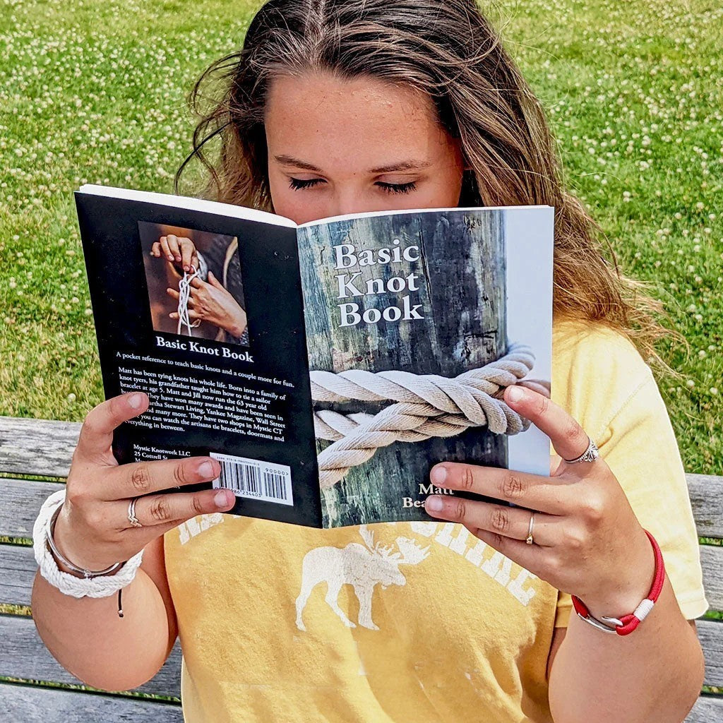 Mellow Monkey Basic Knot Book held by a woman outdoors, featuring illustrated instructions for 17 classic knots.