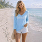 Mellow Monkey light blue lightweight knit sweater with BEACH graphic worn by a woman on a sandy beach.