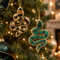 Mellow Monkey handmade beaded snake ornaments with sequins hanging on a Christmas tree in green and gold patterns.