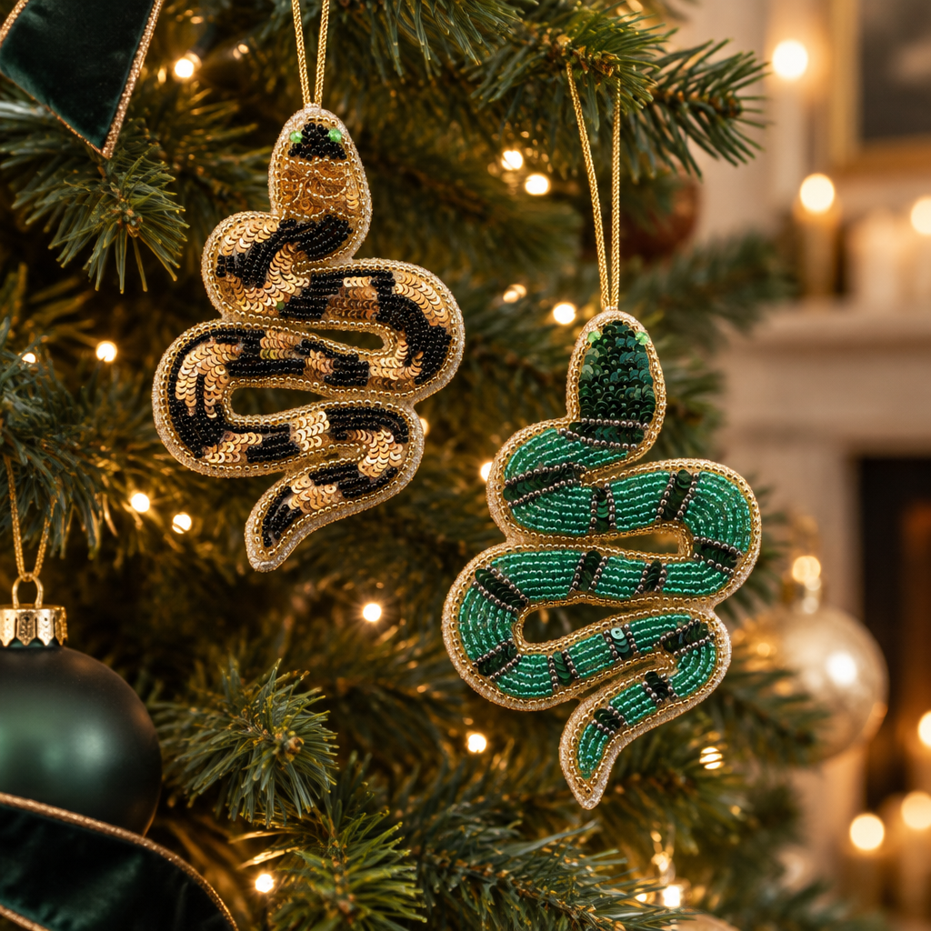 Mellow Monkey handmade beaded snake ornaments with sequins hanging on a Christmas tree in green and gold patterns.