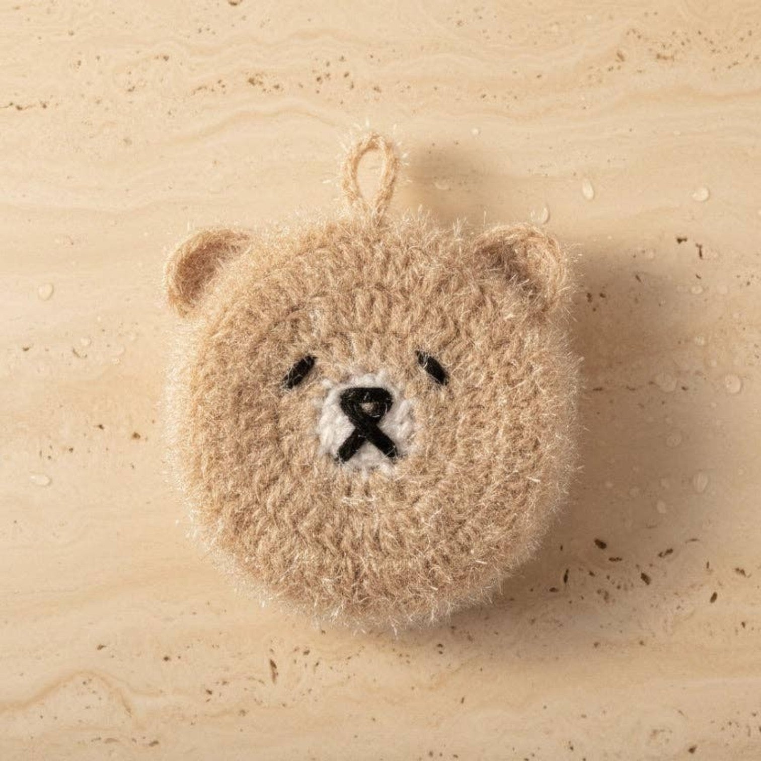 Mellow Monkey Good News Bears scrubby sponge in taupe, shaped like a bear face with black embroidered features and a hanging loop.