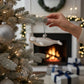 Mellow Monkey white blown glass beluga whale holiday ornament, 5.5-in, hanging on a frosted Christmas tree.