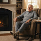 Mellow Monkey brown argyle socks with Best Grandpa Ever text worn by a smiling elderly man sitting in a cozy armchair