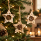 Mellow Monkey birch bark star ornaments with iron cut-out icons hanging on a decorated Christmas tree
