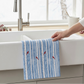 Mellow Monkey waffle dish towel with blue birch tree and red cardinal print hanging over a white farmhouse kitchen sink