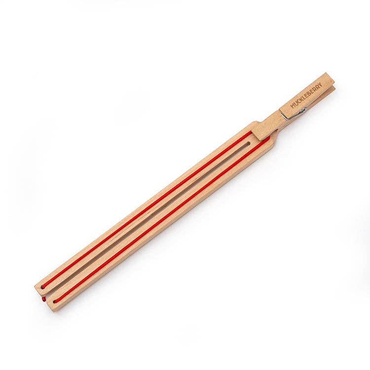 Mellow Monkey Huckleberry paper plane launcher made of FSC birch wood with red elastic bands on a white background.